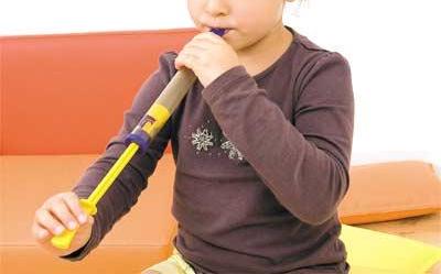Bambino che suona il flauto a coulisse in legno Montessori