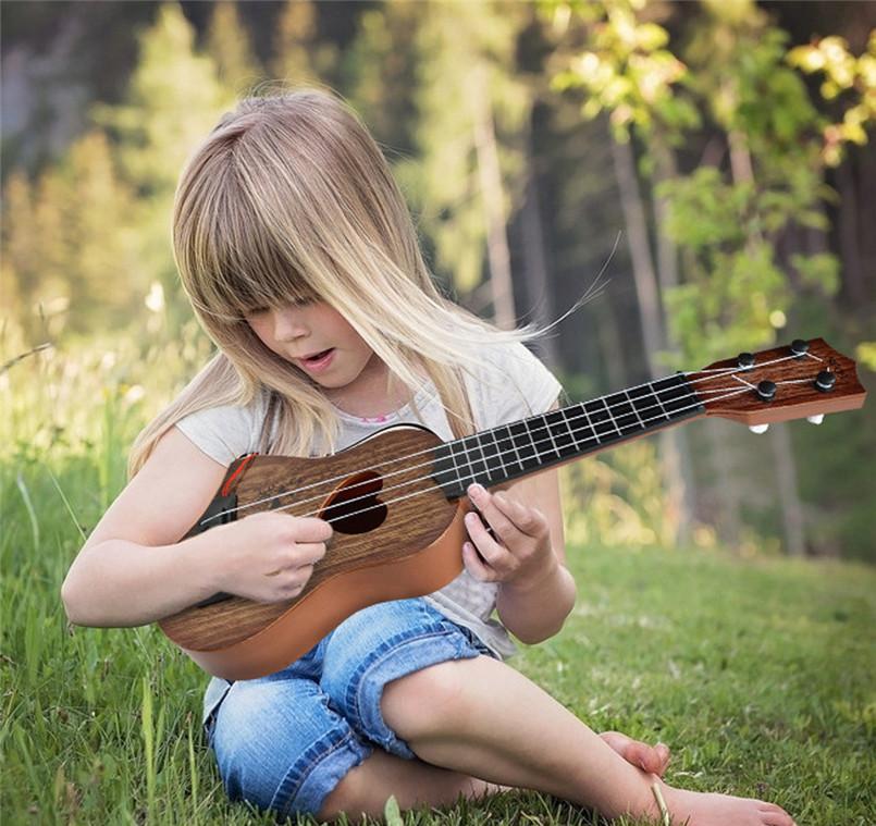 Bambino che suona la chitarra acustica in legno Montessori con corde in nylon