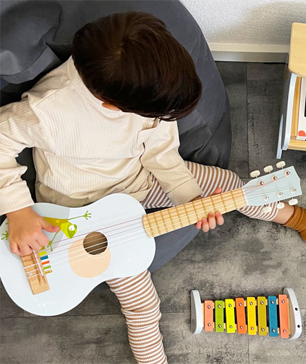 Bambino che suona la chitarra acustica in legno per l'educazione musicale Montessori